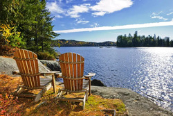 An image of two chairs sat on the shore of one of the great lakes